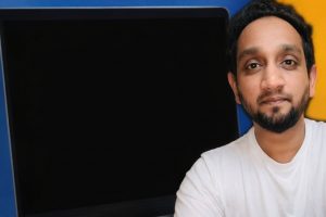 Man framför en bärbar dator med svart skärm. Kan representera teknisk användning i hemmet.